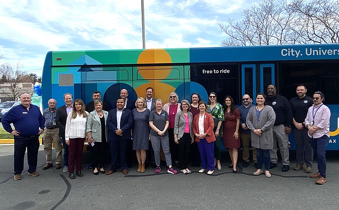 Ceremony participants gather in front of one of the newly wrapped CUE buses.