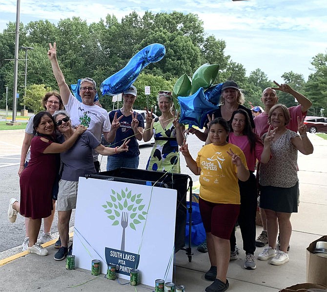 Volunteers put two fingers up, signifying the 2 million pound mark of food and toiletries distributed to those experiencing food insecurity by  South Lakes PTSA Food Pantry as of July 18.