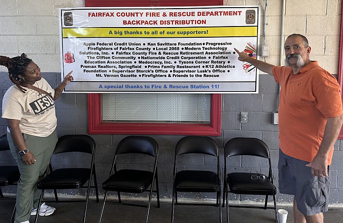 Volunteer Jennifer Harris and retired firefighter Domenick Iannelli point to the banner which lists the donors for the school supply program.