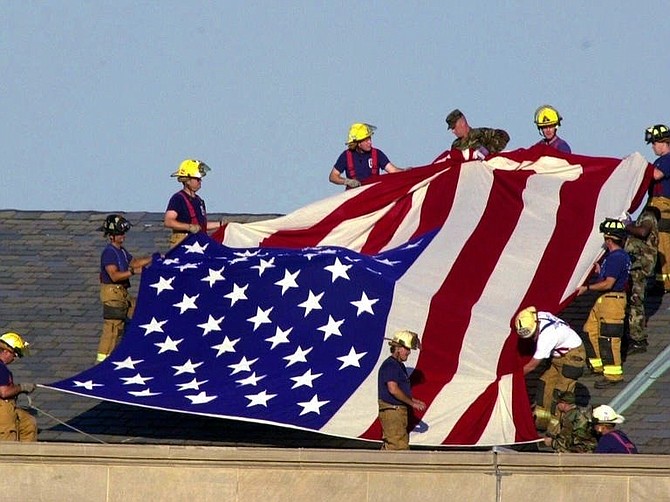 Lt. Jim Morris, far bottom right, and fellow firefighters from Alexandria and Fairfax County Fire and Rescue Station 11 join soldiers atop the Pentagon to unfurl an American flag during rescue and recovery efforts Sept. 12, 2001. Morris’s brother Seth perished in the attacks on the World Trade Center.