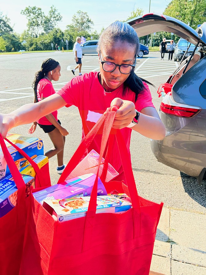 A young volunteer with Food for Neighbors at Irving Middle School helps to unload food and toiletry donations bound for partnering schools in the Springfield area.