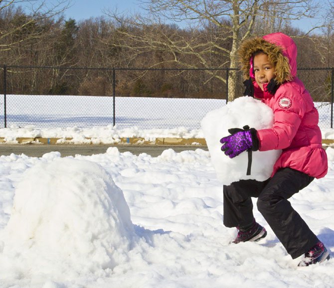Mariah, hard at work, builds a snowman in her front yard. 