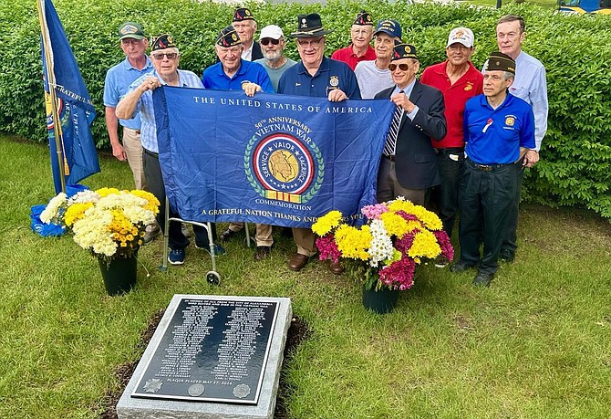 Local veterans gather for a photo at the plaque bearing the 68 names of Alexandrians who were killed in the Vietnam War during a dedication ceremony May 27 at the city’s Union Station.