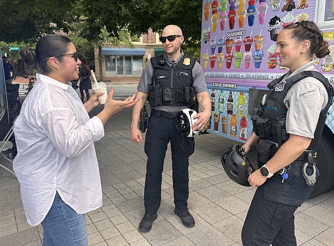 Liliana Rosen chats with Captain Jason North and Officer Arielle Deem of the neighborhood initiative unit, at National Night Out at John Carlyle Square on Aug. 6