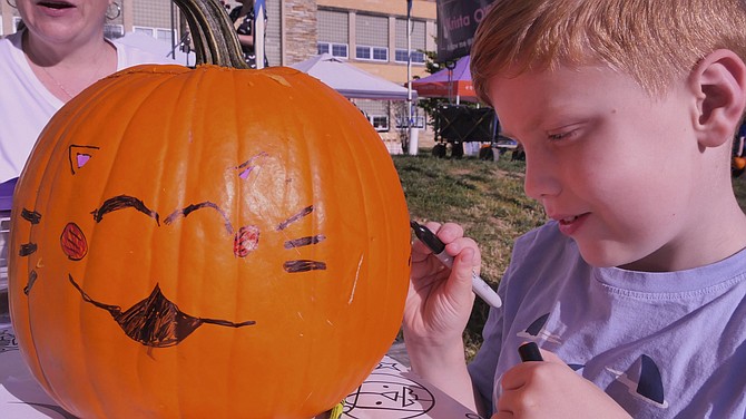 Seven-year-old James Meikle puts the finishing touches on his pumpkin’s cat face.