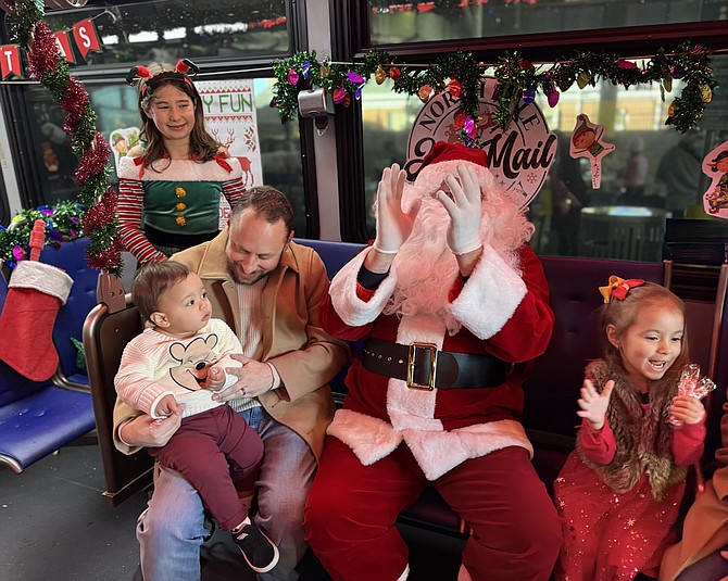 Elf Betty and Santa watch, as children Rafael, 1, and Sofia, 3, enjoy the wonders of Christmas, with parents Nicholas and Paola (not pictured) Ballasey of Lorton