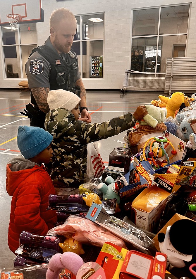 Police Officer Dylan Ignacio helps a child pick out a Christmas toy at the Firefighters and Friends toy drive Dec. 14 at Patrick Henry Elementary School.