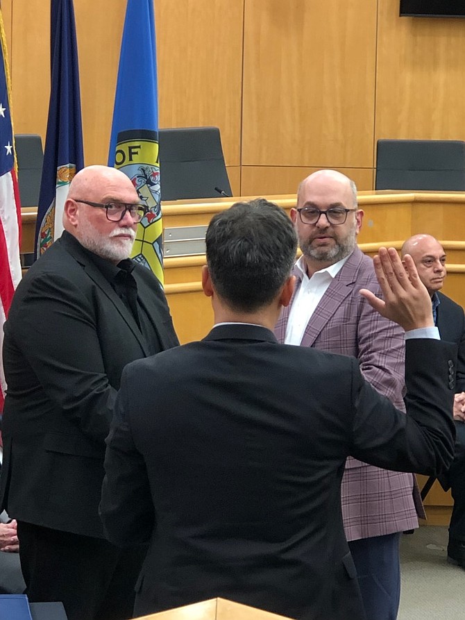 Keven LeBlanc is sworn in as the mayor of the Town of Herndon on Jan. 7, 2025, with his hand on the Bible his husband, Scott Mayhugh, holds. The Bible belongs to the couple’s “dear friend,” Steve Mundt. It was the Bible that was with Mundt in all of his active military deployments. Inside the Bible are the memorial cards for every soldier that died in action under Mundt during those deployments.