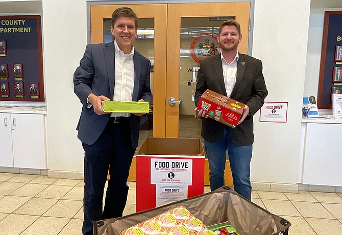 Fairfax County Board Supervisor Walter Alcorn (left) helps Kyle McDaniel, Fairfax County School Board Member At-Large, unload his donations to the Food for Neighbors drive at the North County Government Center.