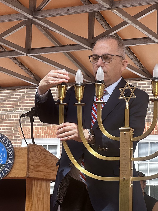 Virginia State Senator Adam Ebbin (D-39) lights the first candle on the candelabrum donated to the city by Charlene Schiff, a Holocaust survivor, and her husband Brig. Gen. Edwin Schiff during the Days of Remembrance ceremony for victims of the Holocaust April 24 at Market Square.