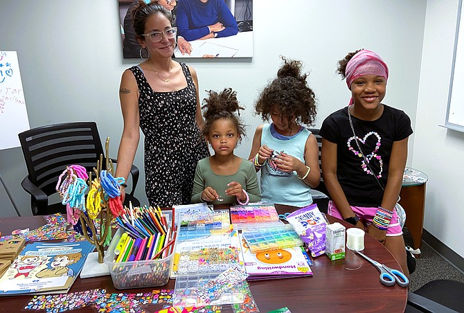 Jennifer Erazo watches while daughter Jaliyah, 8 (center), makes decorative backpack rings with friends and sisters (from left) Maleah, 5, and Taleah, 11.