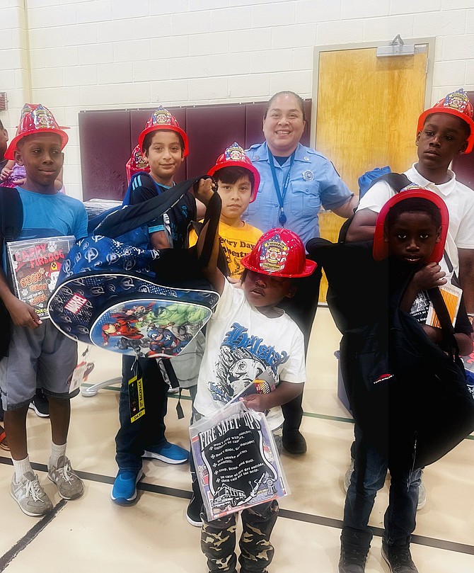 Firefighter Leslie Palucho stands with students showing off their new backpacks at the Firefighters and Friends back-to-school backpack giveaway Aug. 10 at Charles Houston Recreation Center.