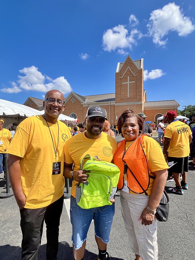 Rev. Jonathan T. G. Wilkins Sr., senior pastor, poses as he holds one of the 2,500 backpacks to be donated to students pre-k through grade 12. Wilkins is joined by Fairfax County Executive Bryan Hill and Angela Cesear lead person at the 2nd Annual Back-to-School Festival held at Mount Olive Baptist Church in Centreville Aug. 9.