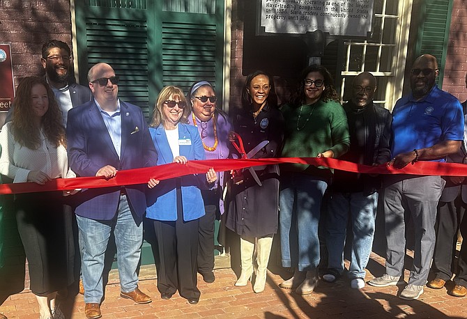 Mayor Alyia Gaskins, fourth from right, prepares to lead dignitaries in cutting the ribbon to celebrate the end of the exterior restoration of Freedom House Nov.8 on Duke Street in Old Town.