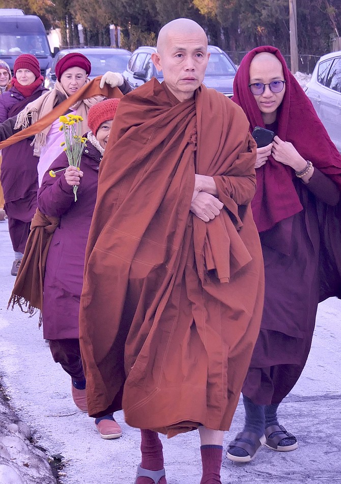 Ven. Bhikku Pannakara accepts a flower from a bystander along Glebe Road.