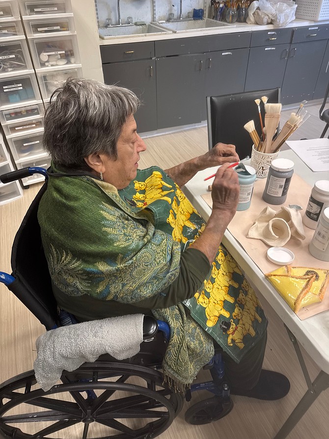 Bryna Freyer, a retired art historian, paints a delicate blue rim on a clay vessel during a studio session at The Jefferson.
