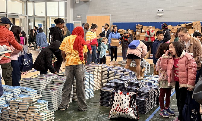 Families and teachers crowd the event with bags, boxes, and carts searching for books