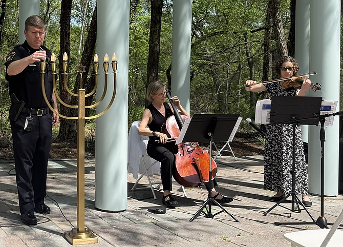Sheriff Sean Casey lights a candle during the Days of Remembrance ceremony April 14 at the Charles E. Beatley Jr. Central Library as musicians Sarah Hover and Jane Pollner perform an interlude.