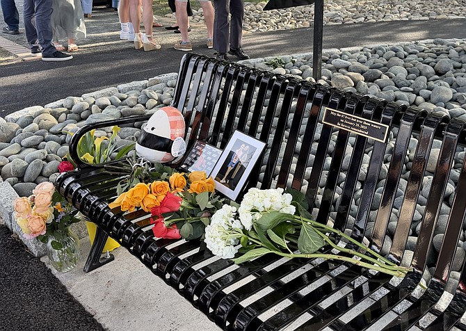 Flowers and memorabilia are left on a bench dedicated to  the victims of the 2025 Potomac River mid-air collision during a dedication ceremony June 1 at Rivergate City Park.