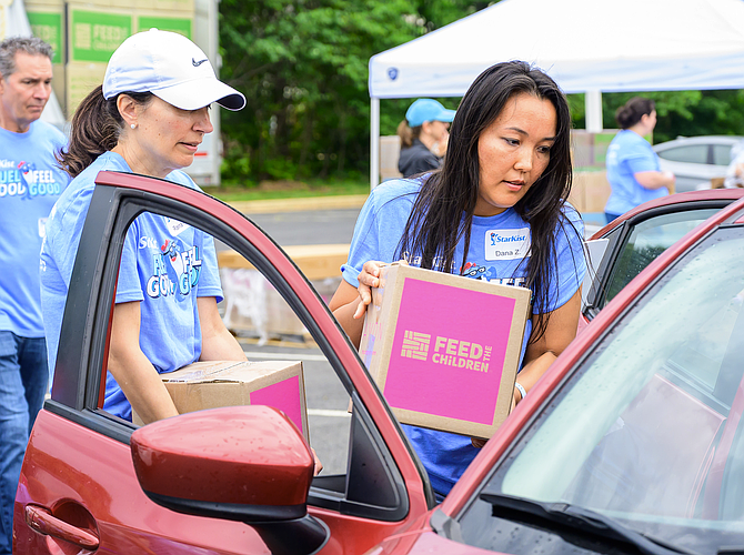 Volunteers from Starkist, headquartered in Reston, distribute resource kits designed to support a family of four with up to 20 meals during the fifth annual Resource Rally in Herndon held at Floris United Methodist Church.